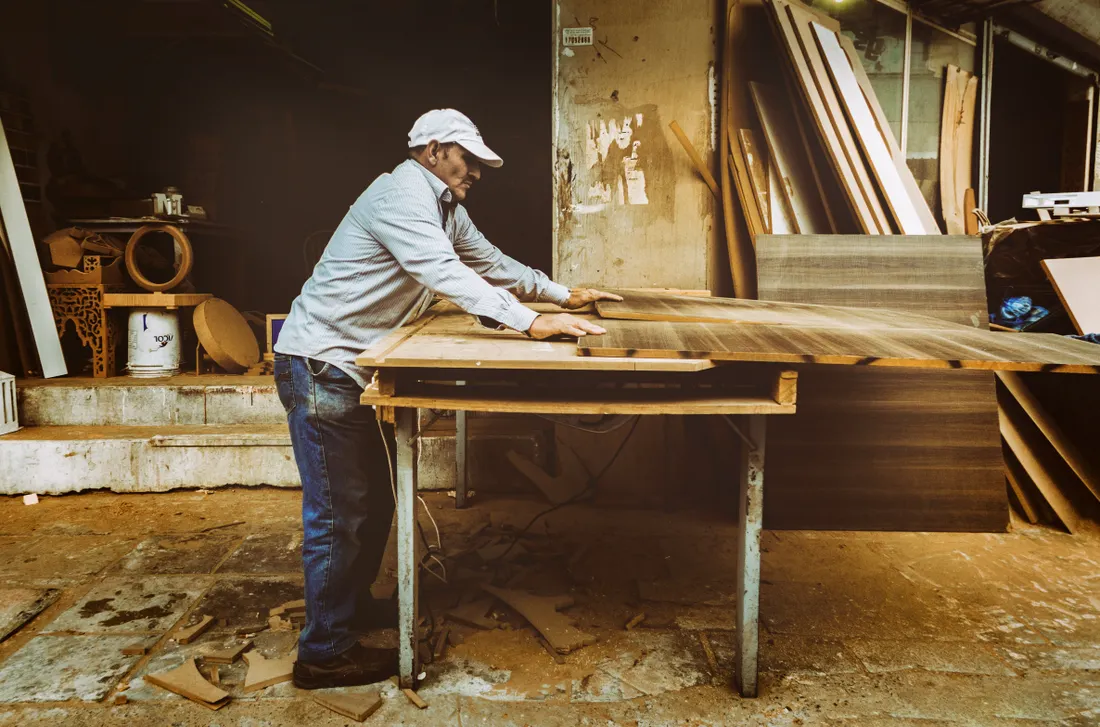 A carpenter working at a bench in a furniture workshop