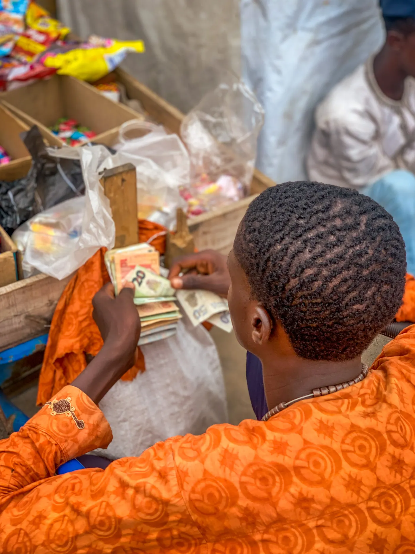 A market trader counting naira notes at his stall